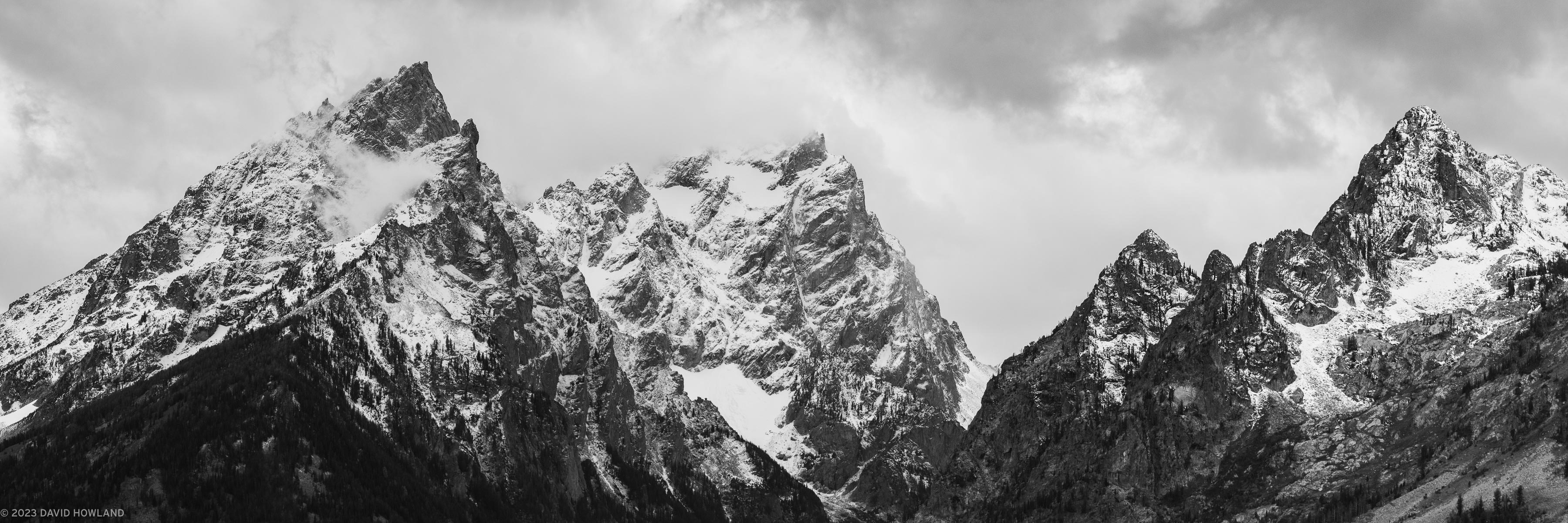 A black and white photo of storm clouds gathering over the snowy high peaks of the Teton Range in Grand Teton National Park, WY.
