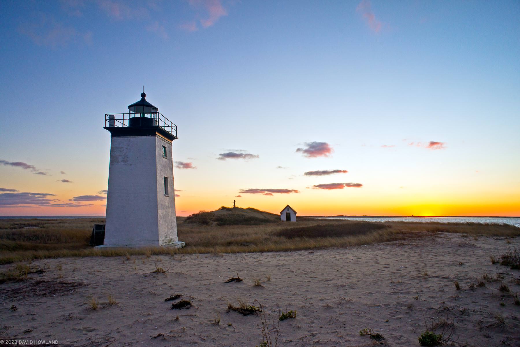 A photo of sunset behind Long Point Lighthouse on the beach in the Cape Cod National Seashore