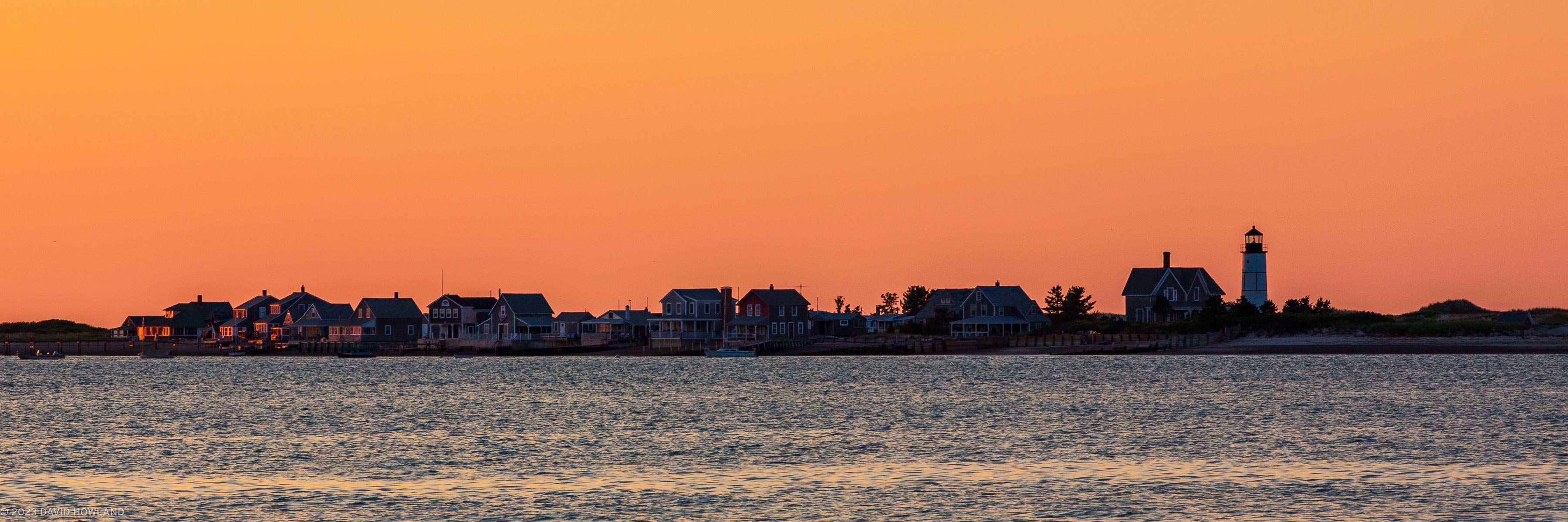 A panorama photo of a bright orange sunset at Sandy Neck Lighthouse in Barnstable, MA on Cape Cod.