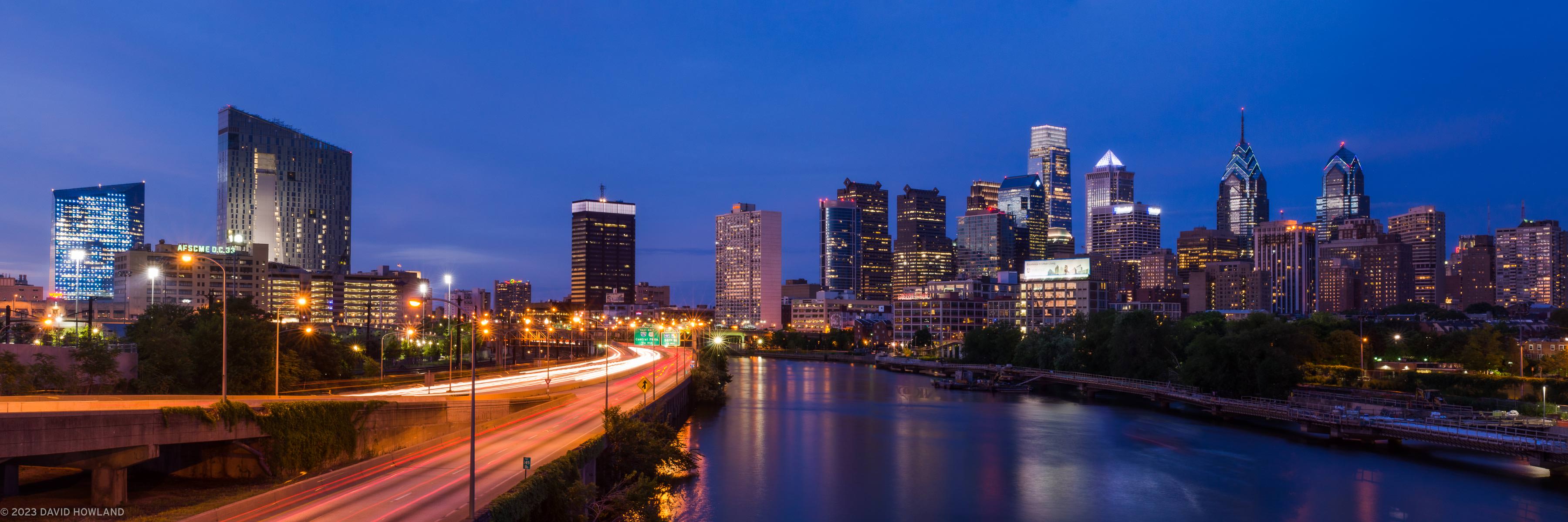 A panorama photo of the Philadelphia skyline and the Schuylkill River taken at sunset from the South Street Bridge