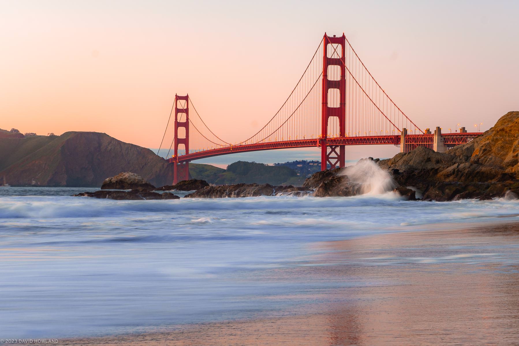 A photo of a pastel orange sunset behind the Golden Gate Bridge in San Francisco, California.
