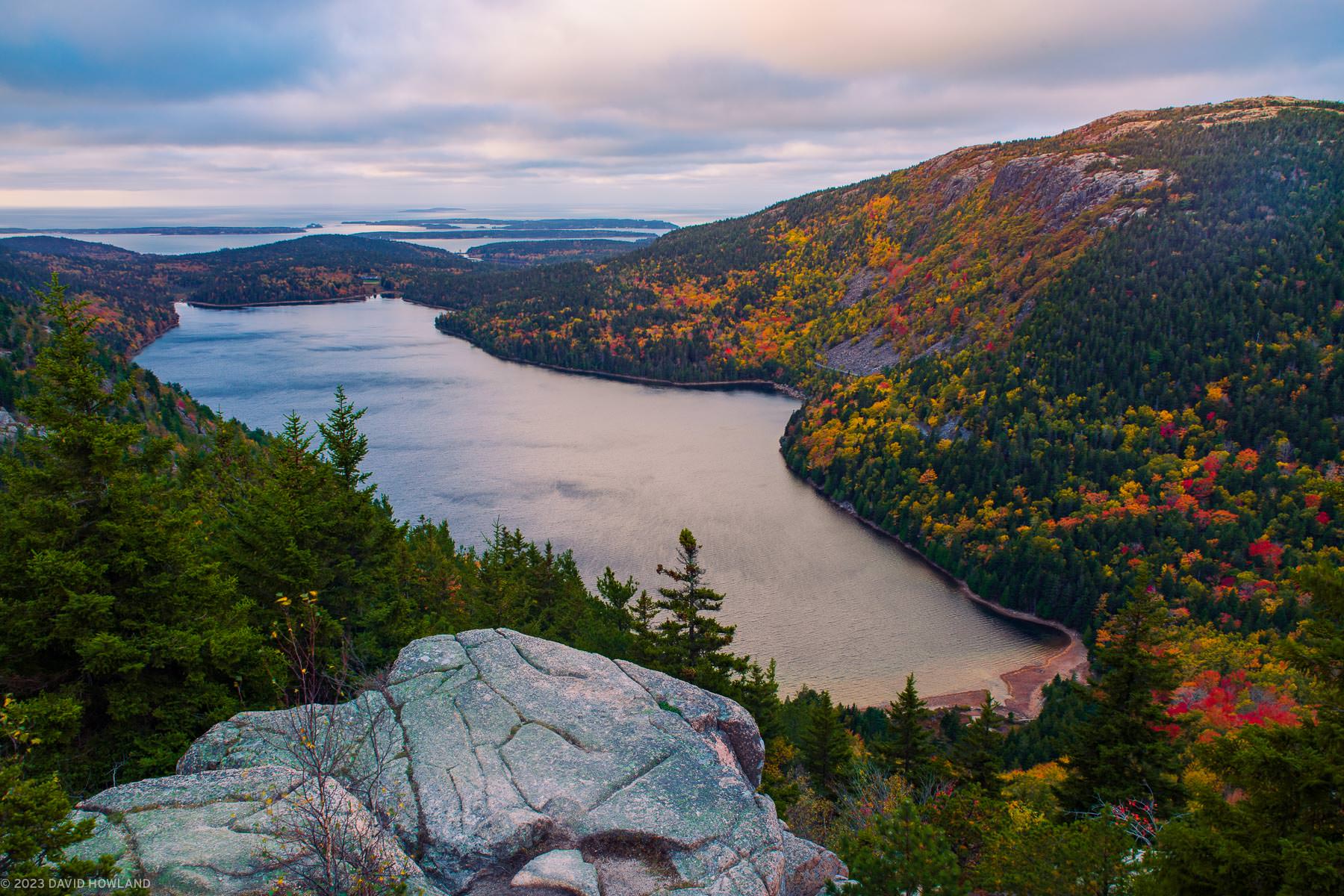 A photo of clouds at sunrise over the colorful foliage of Acadia National Park and Jordan Pond