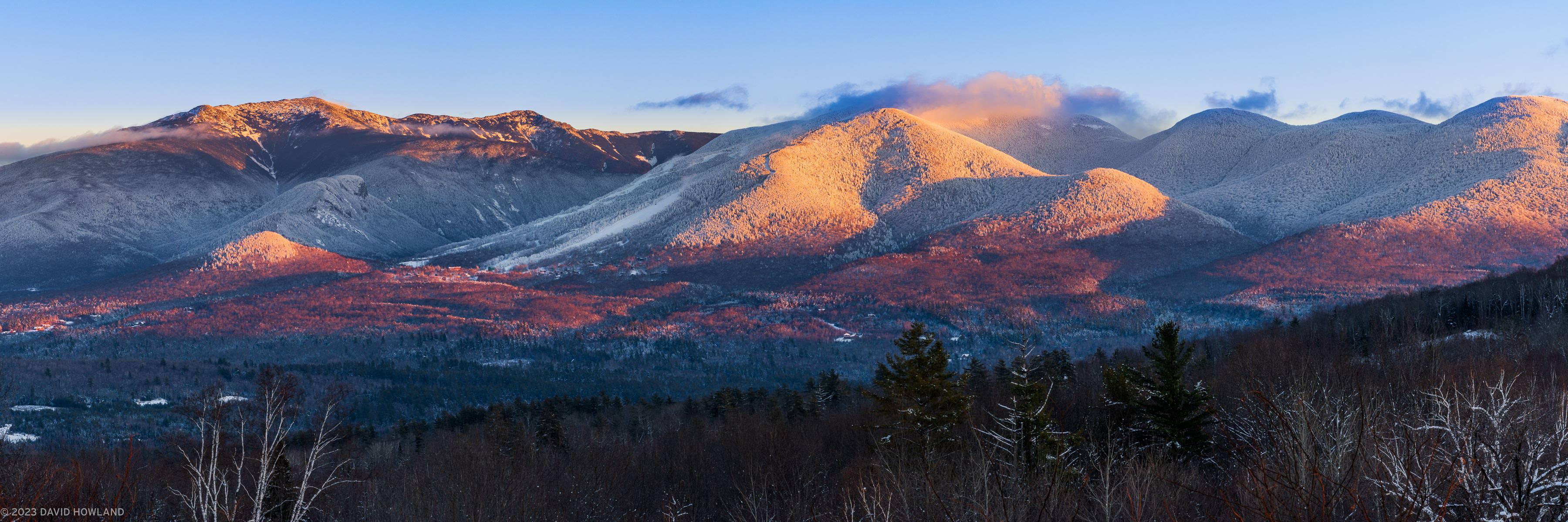 A panorama photo of alpenglow on the snow covered peaks of Franconia Notch in the White Mountains of New Hampshire.