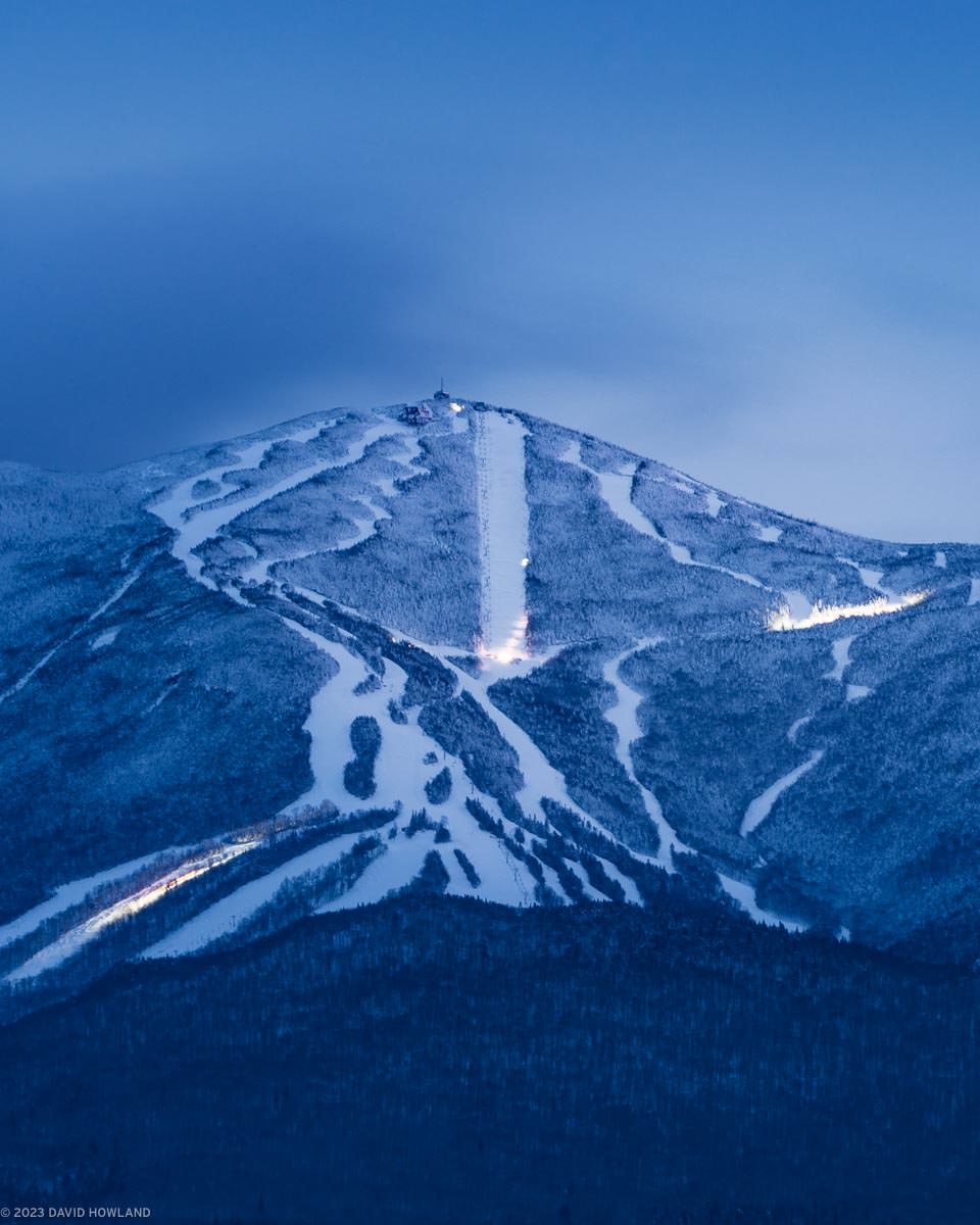 A photo of the ski trails of Cannon Mountain at dusk lit up by the grooming machines traversing the mountain