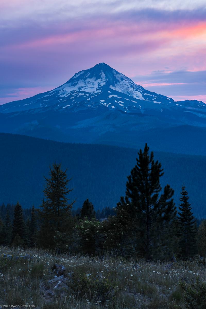 A photo of sunset behind the snow covered slopes of Mount Hood in Oregon.