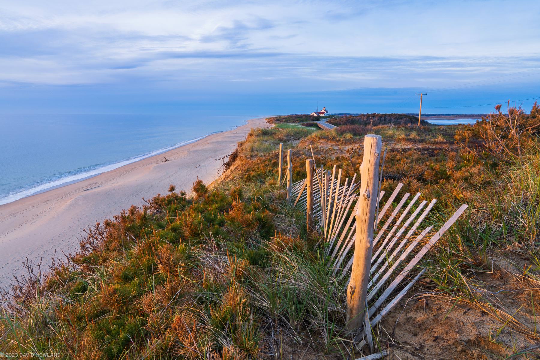 A photo of a twisted and worn wooden beach fence in the sand dunes of Coast Guard Beach in the Cape Cod National Seashore