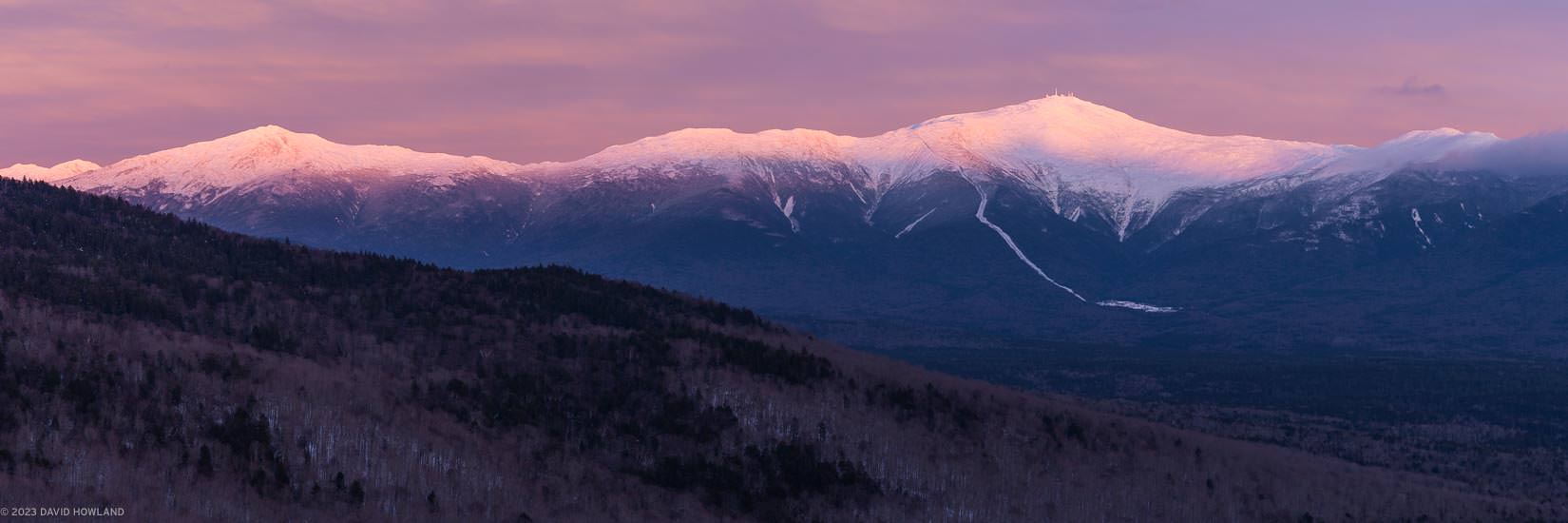 A panorama photo of sunset alpenglow lighting up Mount Monroe, Mount Washington, and Mount Jefferson in the Presidential Range of New Hampshire.