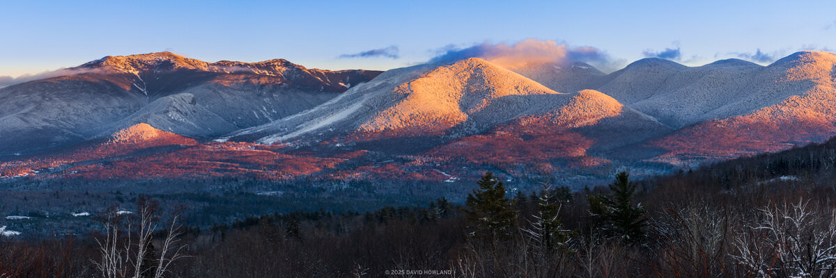 A panorama photo of alpenglow on the snow covered peaks of Franconia Notch in the White Mountains of New Hampshire.