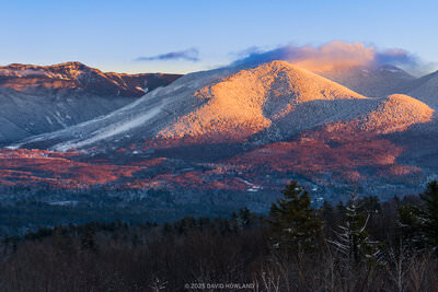 A panorama photo of alpenglow on the snow covered peaks of Franconia Notch in the White Mountains of New Hampshire.
