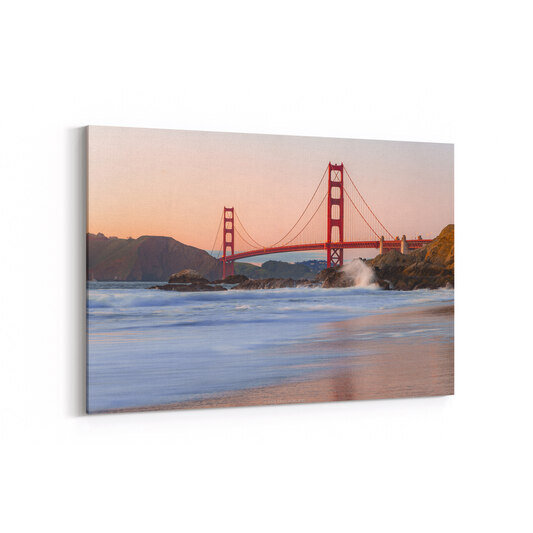 A photo of a pastel orange sunset behind the Golden Gate Bridge in San Francisco, California.