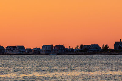 A panorama photo of a bright orange sunset at Sandy Neck Lighthouse in Barnstable, MA on Cape Cod.