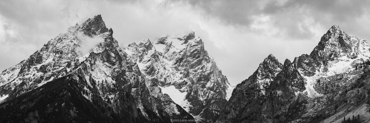 A black and white photo of storm clouds gathering over the snowy high peaks of the Teton Range in Grand Teton National Park, WY.