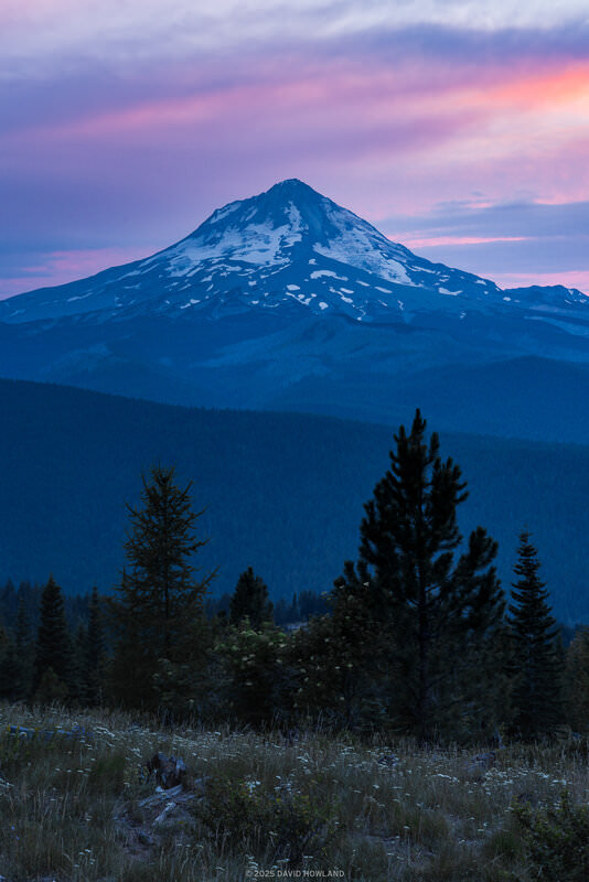 A photo of sunset behind the snow covered slopes of Mount Hood in Oregon.